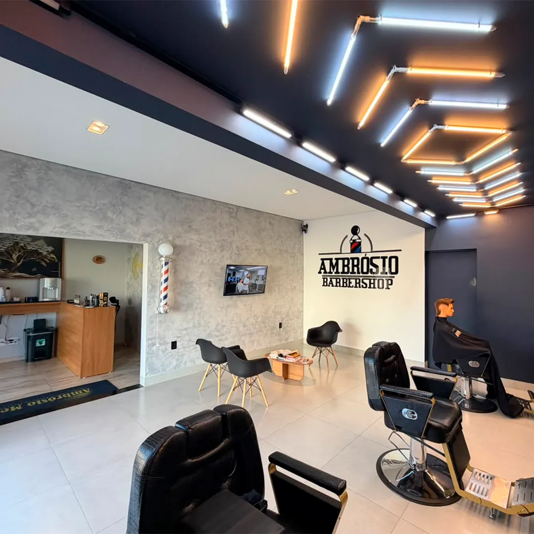 Interior da Ambrósio Barbershop com iluminação e cadeiras