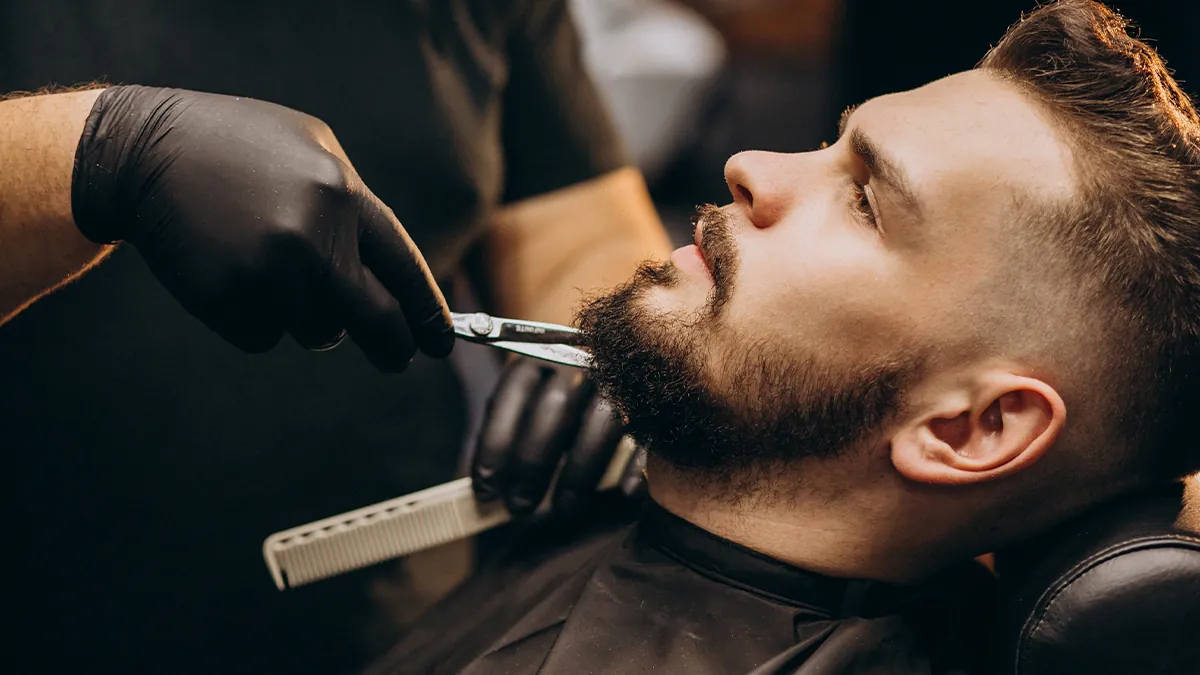 Barbeiro fazendo o acabamento da barba com navalha